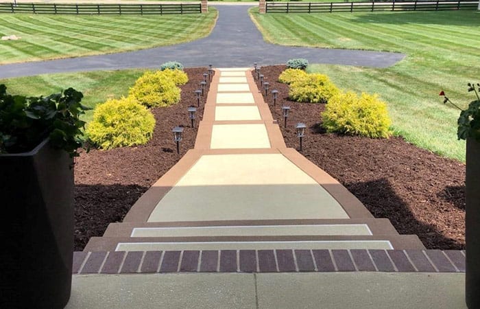Decorative concrete walkway with stamped borders leading to front steps by Bricks-n-Stones